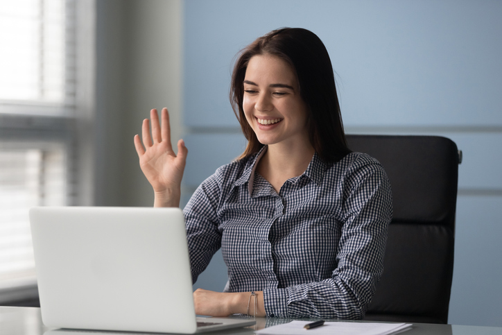 friendly woman waving at laptop while on a video call